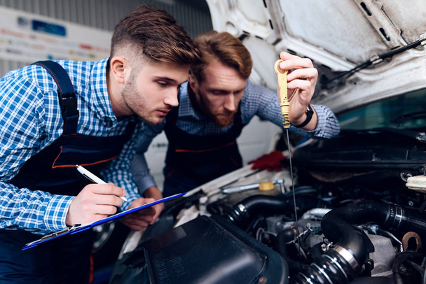 Father and son work at the auto service. Two mechanics work with the details of the car. - Fotó, kép