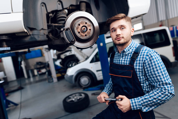 Een jonge man werkt bij een tankstation. De monteur houdt zich bezig met het repareren van de auto. - Foto, afbeelding