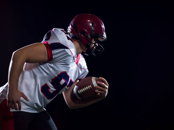 American football player holding ball while running on field - Valokuva, kuva