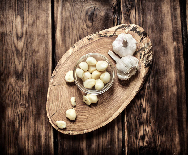 Peeled cloves of garlic on a wooden trunk.  - Fotó, kép