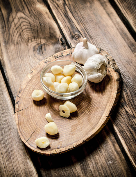 Peeled cloves of garlic on a wooden trunk.  - Foto, Imagen