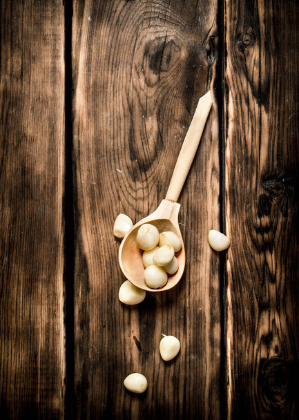 Peeled cloves of garlic in a wooden spoon.  - Photo, image