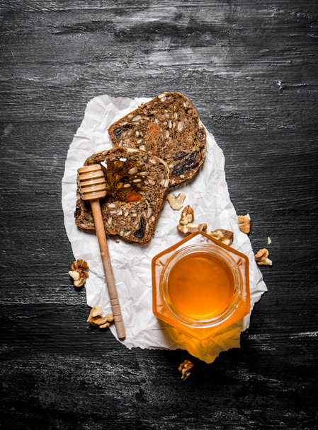 Sweet honey in glass jar and fruit bread with walnuts.  - Fotografie, Obrázek
