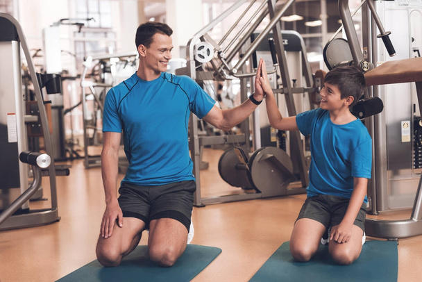 Dad and son in the same clothes in gym. Father and son lead a healthy lifestyle. - Zdjęcie, obraz
