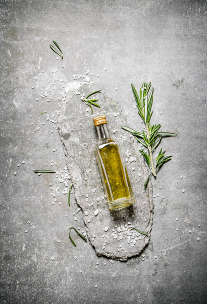 Olive oil in bottle with rosemary and salt.  - Photo, image
