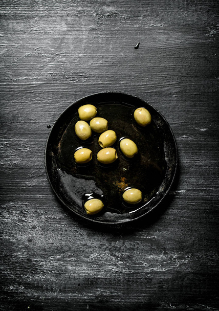 Olives in olive oil. On black rustic background. - Photo, image
