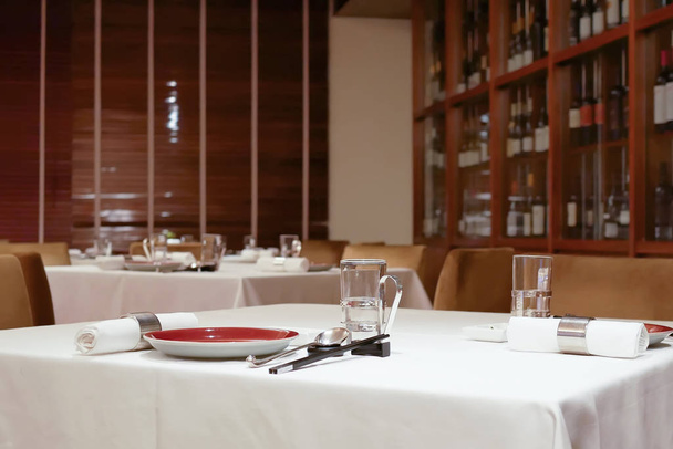 Un lado del gabinete de vino tinto con copas y palillos en la mesa dentro del restaurante
 - Foto, imagen