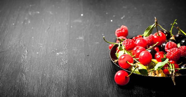 Wild berries in the old plate. On black wooden background. - Fotografie, Obrázek