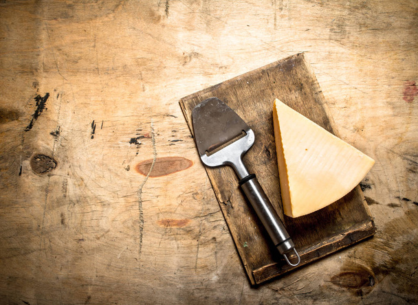 Parmesan cheese with knife on old cutting Board. - Foto, Imagen