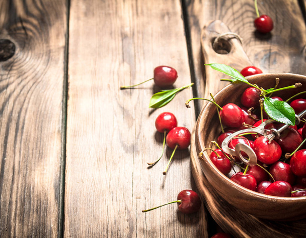 Red cherry in the Cup and metal tool for cherries. - Foto, Imagem