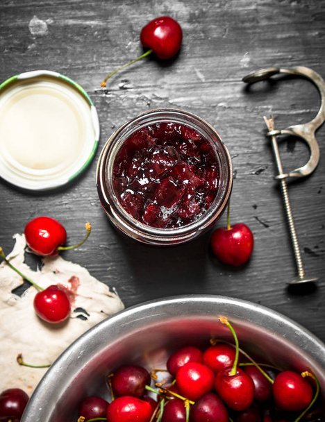 Cherry jam and metal tool for cherries. - Valokuva, kuva