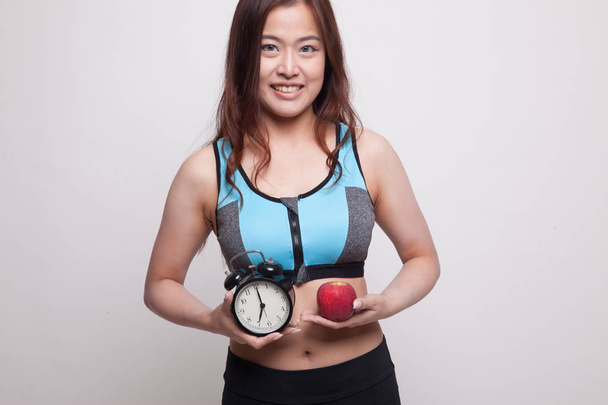 Beautiful Asian healthy girl with clock and apple. - Fotoğraf, Görsel