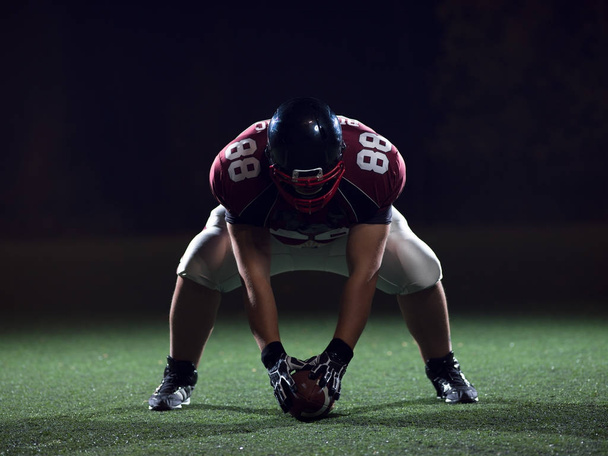 American football player starting football game on american football field at night - Foto, Imagen