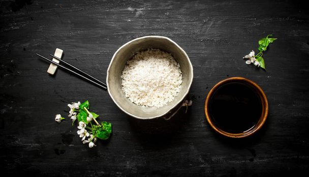 Rice in an old pot and soy sauce. - Фото, изображение