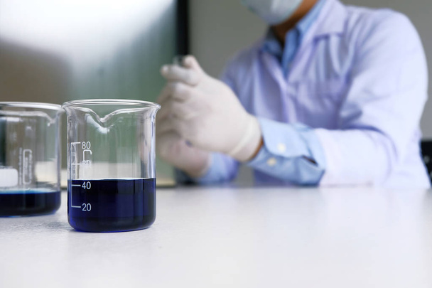 Male medical or scientific laboratory researcher performs tests with blue liquid in laboratory. equipment science experiments concept - Photo, Image