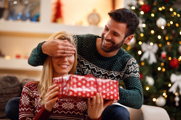 Man covering eyes to woman when giving Christmas gift - Φωτογραφία, εικόνα