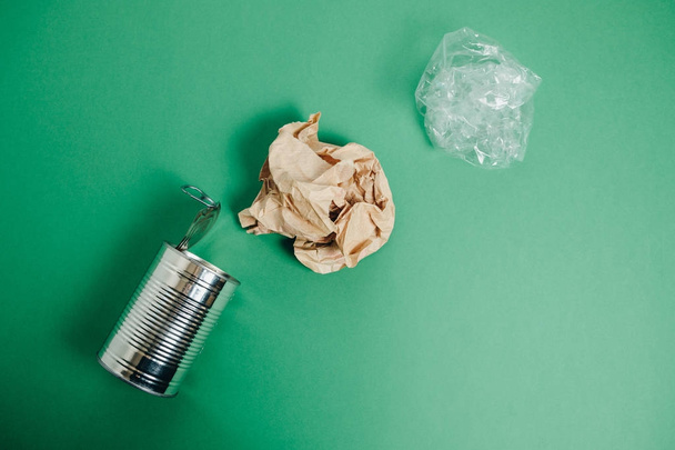 Aluminum jar and crumpled paper on a green background. Top View - Фото, зображення
