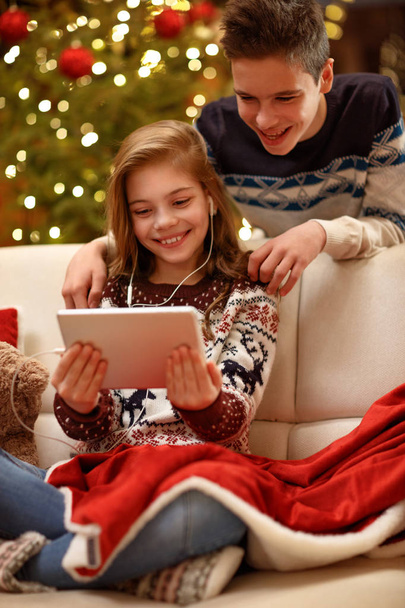 Brother and sister enjoy in Christmas eve with music from tablet - Foto, Imagen