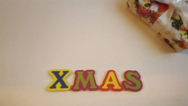 Kolorowe litery przeliterować Xmas na białym płótnie z prezentów świątecznych - Zdjęcie, obraz