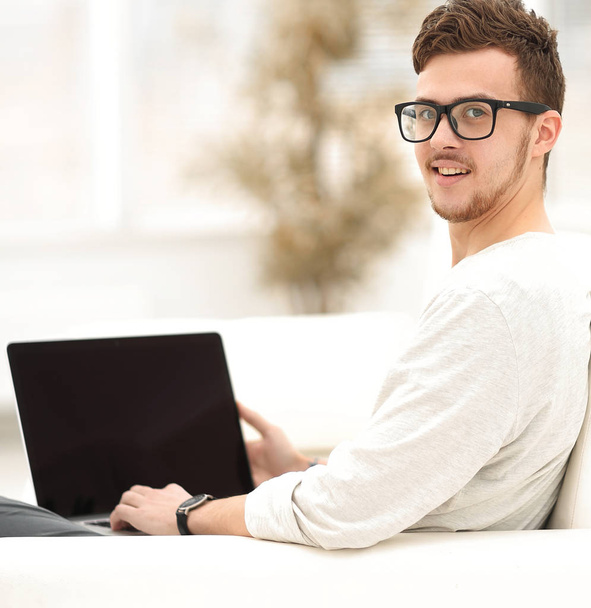 giovane uomo moderno che lavora sul computer portatile seduto in soggiorno
. - Foto, immagini