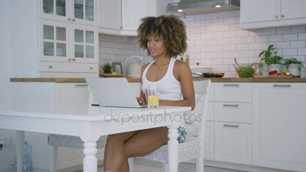 Jeune femme utilisant un ordinateur portable dans la cuisine - Séquence, vidéo