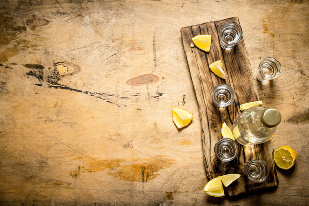 Bottle of vodka with shot glasses and lemon. - 写真・画像