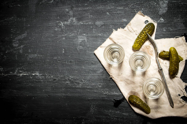 Glasses with vodka and pickled cucumbers on the old fabric. - Zdjęcie, obraz