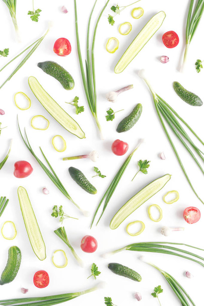 野菜の抽象的な構成。野菜のパターン。食品の背景。平面図です。大小のキュウリ、ニンニク、トマト、白の背景に青ネギ。フレームの垂直方向 - 写真・画像