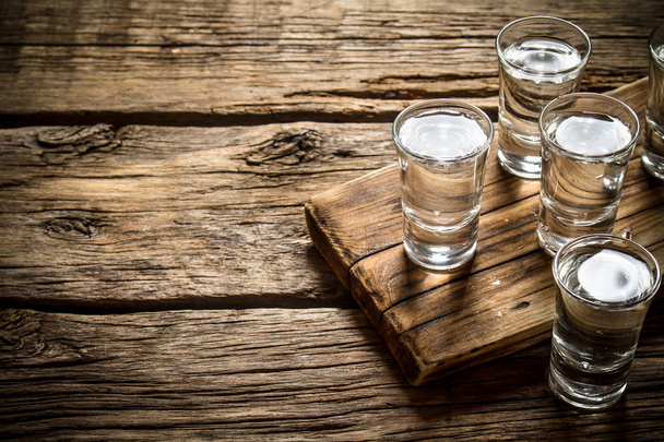 Glasses with vodka on the old Board. - Foto, afbeelding