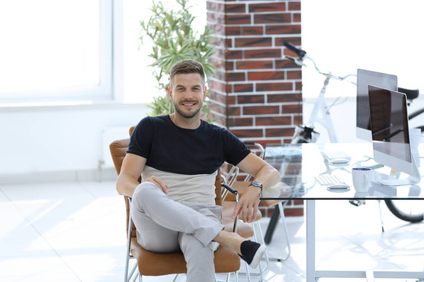 selbstbewusster junger Mann sitzt an seinem Arbeitsplatz - Foto, Bild