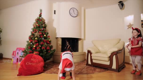良い新年の精神: サンタ クロース、クリスマス ツリー、ギフトバッグ、暖炉 - お祝い服を着て 2 つの世代の家族 - 子供と父親 - 冬の休日を祝って、カメラの前で踊り、愚か者を再生. - 映像、動画