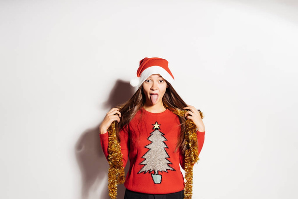 funny young girl showing tongue in red clothes waiting for new year and christmas - Zdjęcie, obraz