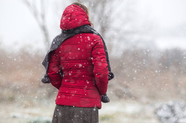 woman in red coat walking in heavy snowfall in the countryside - Foto, imagen