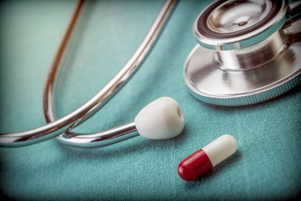 Red and white capsule next to a stethoscope, conceptual image - Photo, Image
