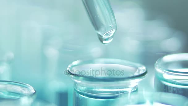 Laboratoriossa pipetillä varustettu tiedemies analysoi sinisen nesteen DNA:n ja molekyylien saamiseksi koeputkista. Nestettä työstävä lääkäri
. - Materiaali, video