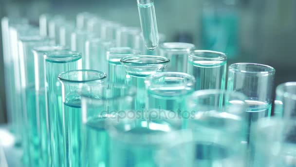実験室では、ピペットを持った科学者が青色の液体を分析し、試験管内のDNAと分子を抽出します。液体を扱う医者. - 映像、動画