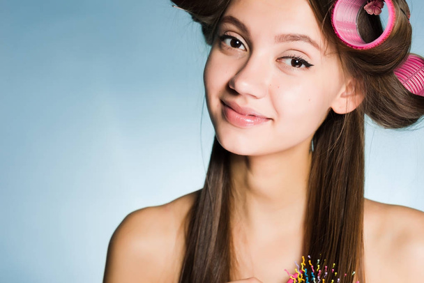 attractive young girl posing, smiling, on her head big pink curlers - Fotó, kép