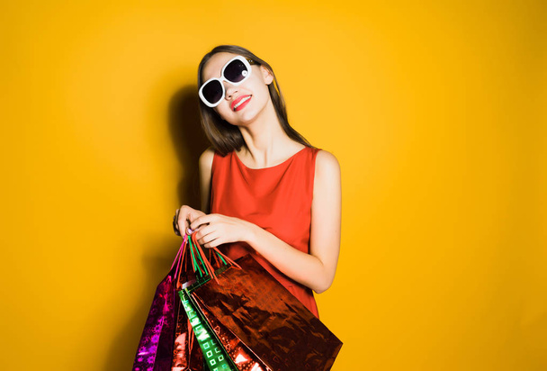 happy stylish girl in sunglasses bought many gifts for the new year on a black Friday - Фото, изображение