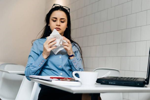 a young busy girl works in a cafe for a laptop, has a sandwich and coffee - Foto, Bild