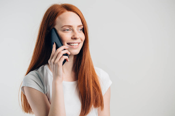 Close up of smiling attractive girl with long hair talking on mobile phone - Zdjęcie, obraz