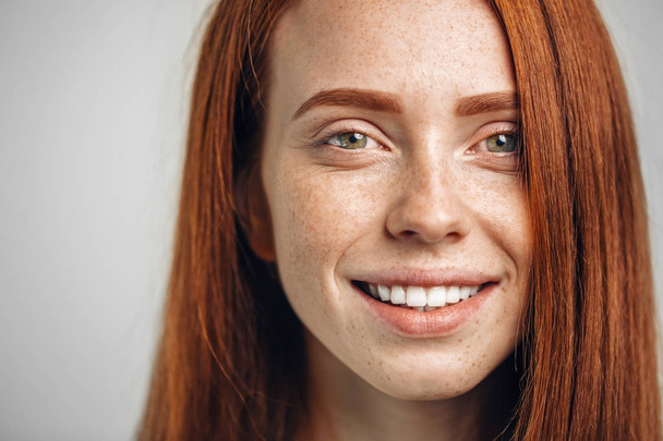 Headshot Portrait of happy ginger girl with freckles smiling looking at camera - Fotó, kép
