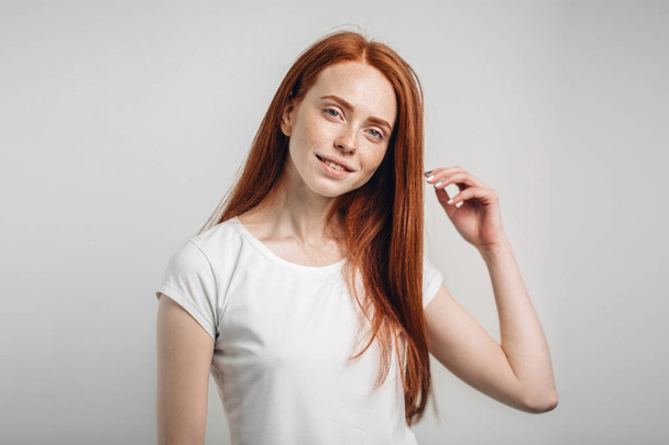 girl smiling with closed eyes touching her red hair over white background - Foto, immagini