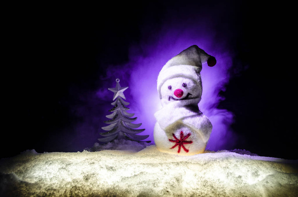 Новий рік. Сніговик випускає подарунки на Новий рік. Білий сніговик, оточений ялинками на вечірньому тлі. Декорування іграшок
 - Фото, зображення
