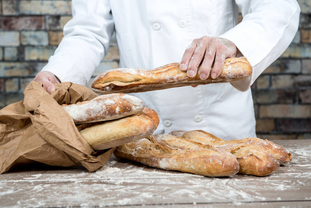 パン屋の伝統的なパンを保持しているフランスのバゲット - 写真・画像