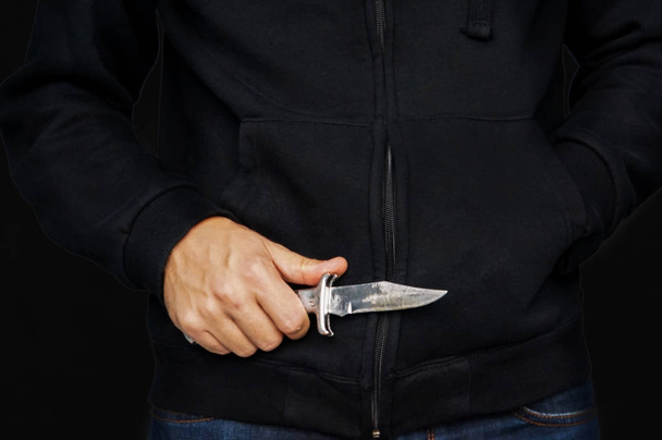 Primer plano de la mano de un joven, sosteniendo un cuchillo, a punto de atacar
, - Foto, imagen