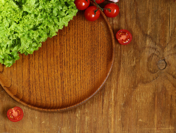 fresh green lettuce leaves and tomatoes on a wooden board - Photo, Image