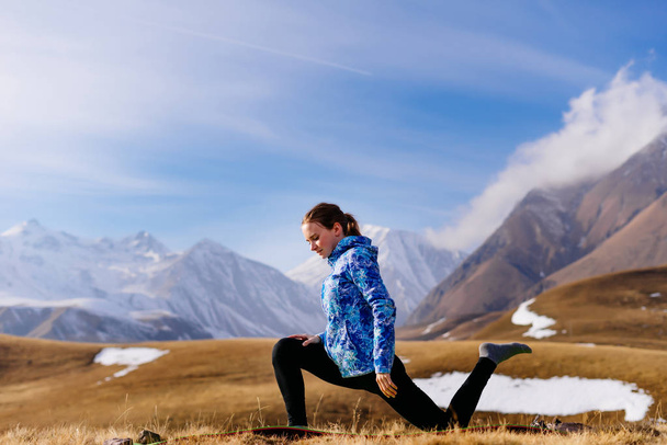 sports young girl doing yoga in the background of the Caucasus mountains, loves to travel - Foto, immagini