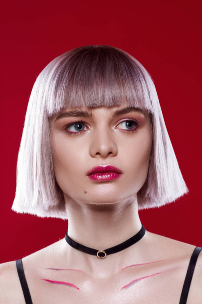 Beautiful girl with blond hair and make-up on a red background - 写真・画像