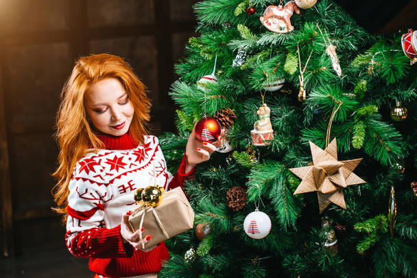 Sexy young woman in sweater is preparing for celebrating New Year at home - Фото, зображення