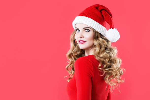 Charming woman with long curly hair and makeup in a santa hat. - Foto, Bild